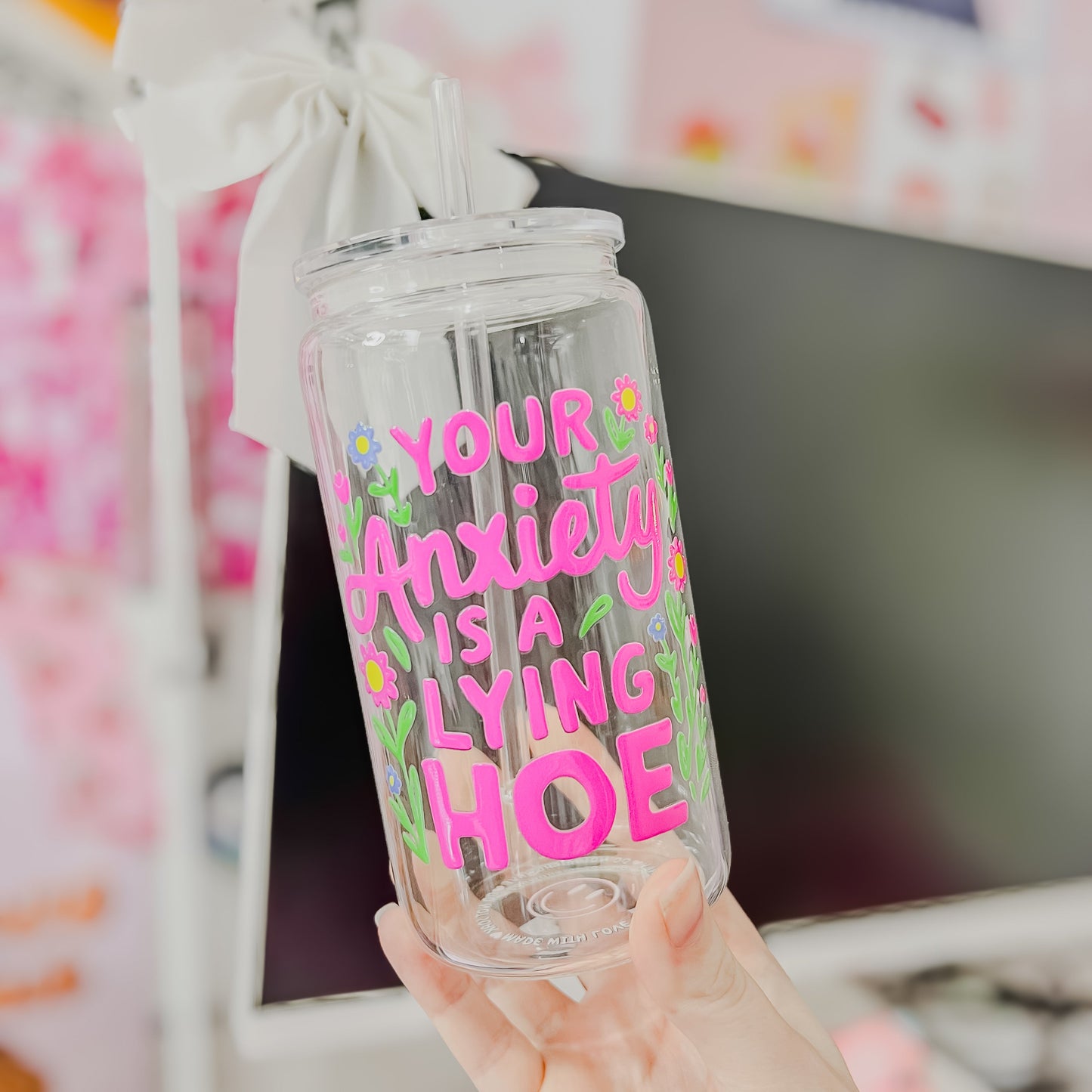 Clear tumbler with colorful text held in front of a blurred background