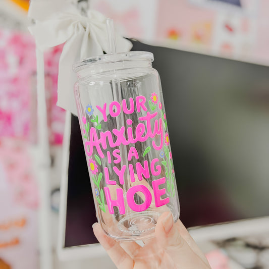 Clear tumbler with colorful text held in front of a blurred background